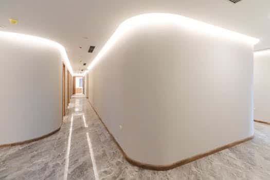 Bright modern hallway with curved walls and soft lighting, showcasing minimalist interior design. دار البناء المتطورة